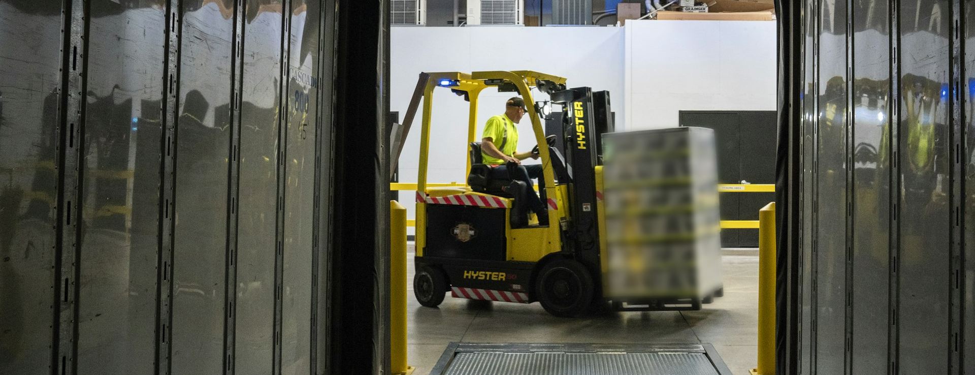 The view from inside an empty trailer as a forklift brings a pallet to the back door